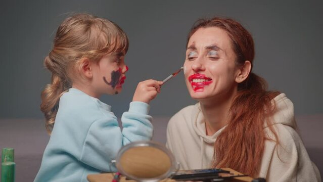 The cute girl paints makeup for her mother. Face painting. Happy moments together. Mother and daughter