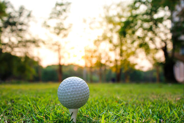 Golf ball set on tee with green, yellow bokeh background and fairy lights.