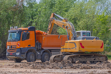 Tipper Truck Loading With Dirt With Excavator Machinery at Construction Site