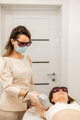 Young woman having laser hair removal underarms in salon