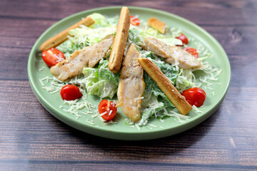 Caesar salad close-up. Grilled chicken breast slices, green romaine salad leaves, croutons and Parmesan, the classic recipe