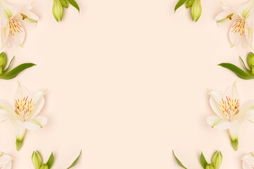 Frame made of alstroemeria flowers and green leaves on a beige background. Gentle springtime...