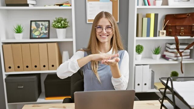 Blonde bombshell, young businesswoman playfully making money hand gesture during office work, sneakily asking for a well-earned salary!