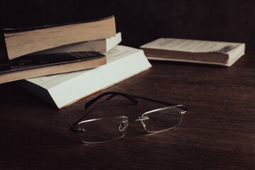 Classic glasses and pile of books on the table. Literature concept. Eyeglasses next to old books. Education and knowledge. Research concept. Book club concept. Read and study.  - 783183099