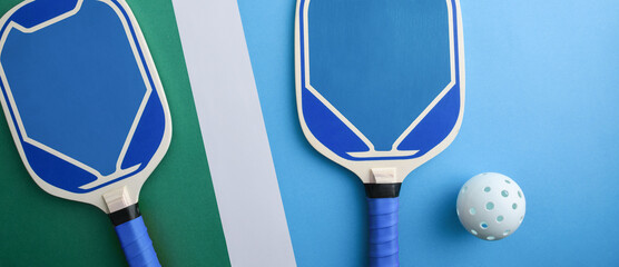 Blue pickleball paddles and white ball isolated on playing court
