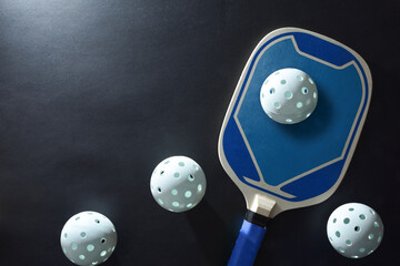 Background with blue pickleball paddle and balls on black