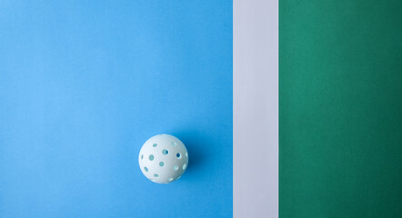 White pickleball ball on blue and green playing surface
