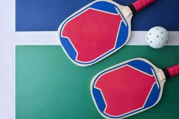 Blue and pink pickleball paddles isolated on playing court