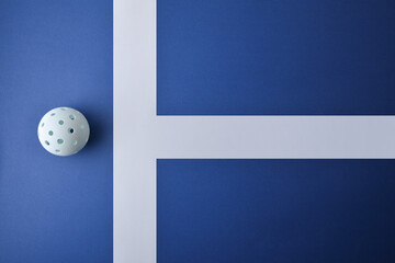 White pickleball ball on blue playing surface top view