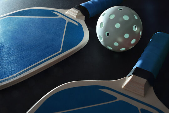 Two pickleball rackets and balls isolated on black table