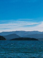 A beautiful blue ocean with mountains in the background. The sky is clear and the sun is shining