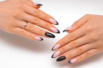 Obraz na płótnie Canvas Festive manicure. Black shiny manicure on long sharp nails close-up on a white background. Reflective design.
