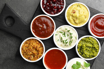 Different tasty sauces in bowls on grey table, top view