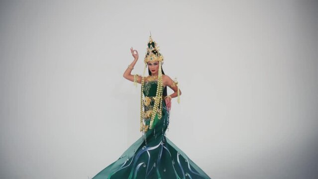 Elegant figurine of a traditional Thai dancer in ornate costume, isolated on a white background.