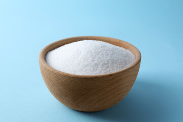 Organic white salt in bowl on light blue background