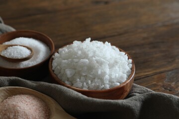 Fototapeta na wymiar Different types of organic salt on wooden table, closeup