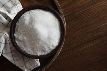 Organic salt in bowl on wooden table, top view. Space for text