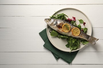 Baked fish with spinach and lemon on white wooden table, top view. Space for text