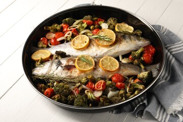 Baked fish with vegetables, rosemary and lemon on white wooden table, closeup
