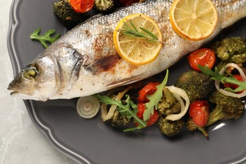 Baked fish with vegetables, rosemary and lemon on grey textured table, top view