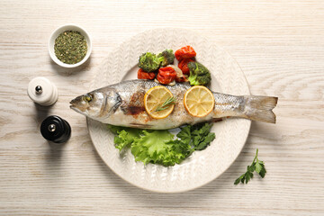 Delicious baked fish and vegetables served on wooden table, flat lay