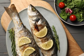 Delicious baked fish served on grey wooden table, top view