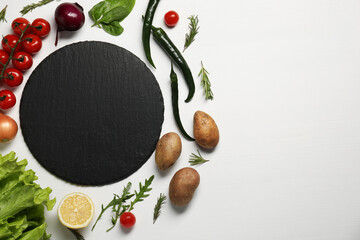 Cooking dinner. Black cutting board and different products on white wooden table, flat lay. Space...