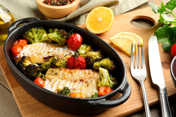 Tasty cod cooked with vegetables served on wooden table