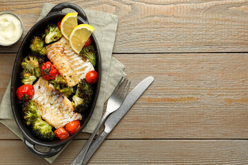 Tasty cod cooked with vegetables served on wooden table, flat lay. Space for text