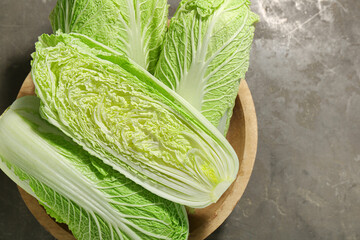 Fresh ripe Chinese cabbages in bowl on gray textured table, top view. Space for text - obrazy, fototapety, plakaty