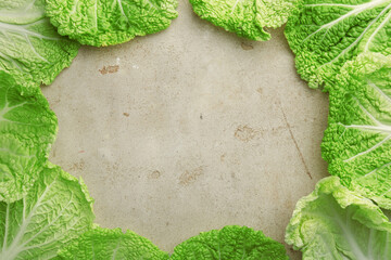 Frame of fresh Chinese cabbage leaves on gray textured table, top view. Space for text
