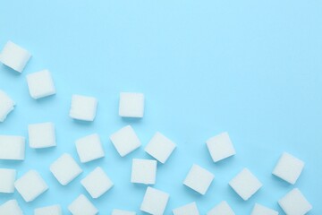 White sugar cubes on light blue background, top view. Space for text