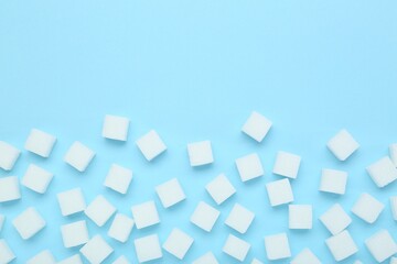 White sugar cubes on light blue background, top view. Space for text