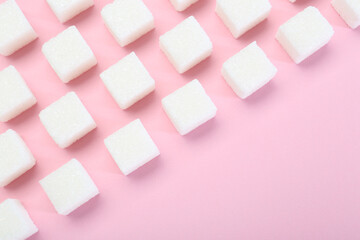 White sugar cubes on pink background, top view. Space for text