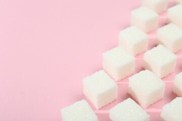 White sugar cubes on pink background, closeup. Space for text