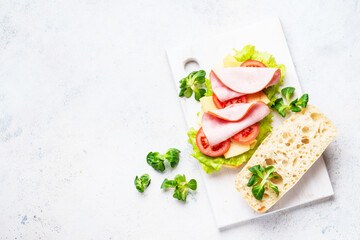 Sandwich with lettuce, cheese, tomatoes and ham. Healthy fast food or snack. Top view on white. - 783198223