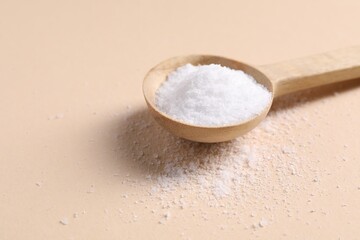 Natural salt with wooden spoon on beige background, closeup