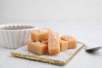 Delicious caramel candies with sea salt on white table