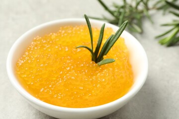 Fresh pike caviar in bowl and rosemary on light grey table, closeup