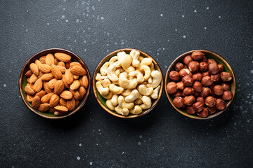 Nuts assortment in bowls at black background. Flat lay with space for text. - 783200077