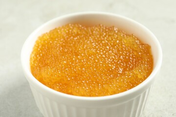 Fresh pike caviar in bowl on light grey table, closeup