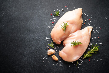 Uncooked chicken breast with spices at black table. Top view with space for text. - 783202015