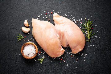 Uncooked chicken breast with spices at black table. Top view. - 783202666