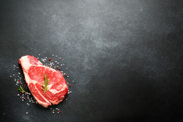 Beef steak. Ribeye steak raw meat on black. Top view with copy space.