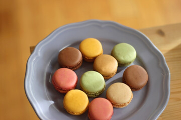 Purple plate filled with pastel macarons on wooden table. Selective focus.
