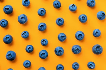 Gordijnen Fresh blueberries arranged on a vibrant orange background, creating a colorful and appetizing topdown composition © SHOTPRIME STUDIO