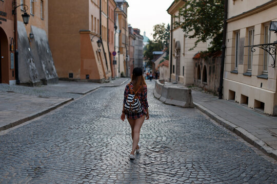Fashionable beautiful girl tourist with a backpack walks through the old town in Warsaw