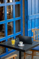 Fototapeta na wymiar Wooden chairs and tables in a cafe with blue wooden doors.