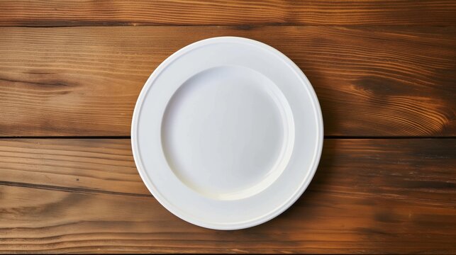 Top view of empty white plate on rustic wooden table.
