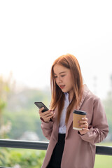 Beautiful Young Asian Woman Going To Work With Coffee Walking Near Office Building. Chilling business woman on phone call while walking